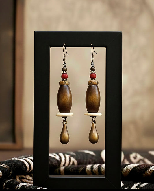 Pair of wooden earrings displayed in a black frame against a neutral background