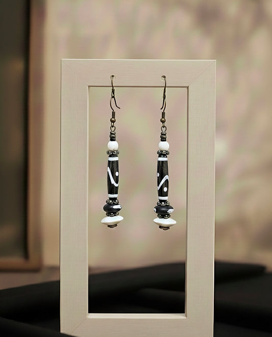 Pair of black and white beaded earrings on a neutral background