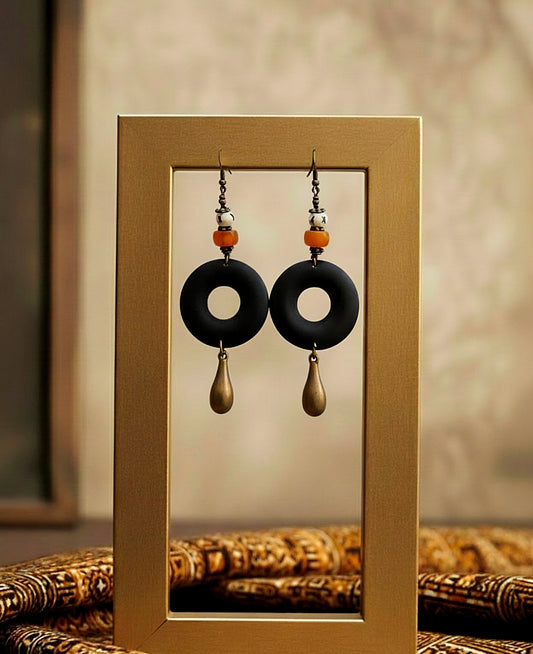 Pair of black and gold earrings displayed in a gold frame.