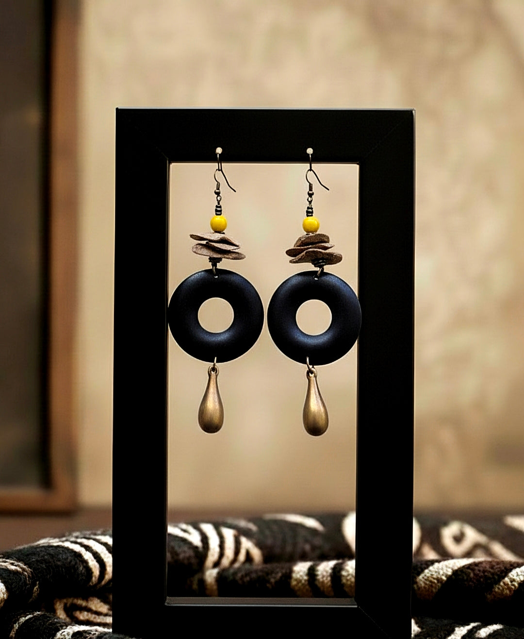 Pair of black and gold earrings displayed in a black frame against a neutral background.