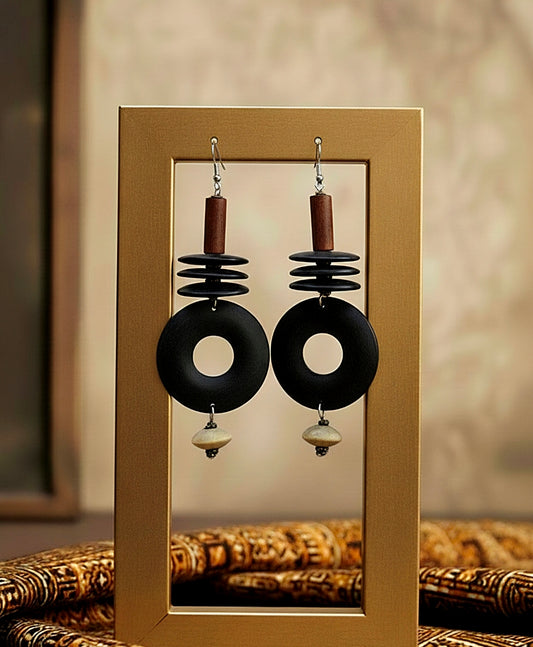 Black earrings with wooden accents on a mirror with a blurred background
