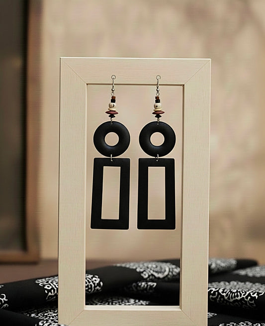 Black wood earrings on a display stand with a blurred background