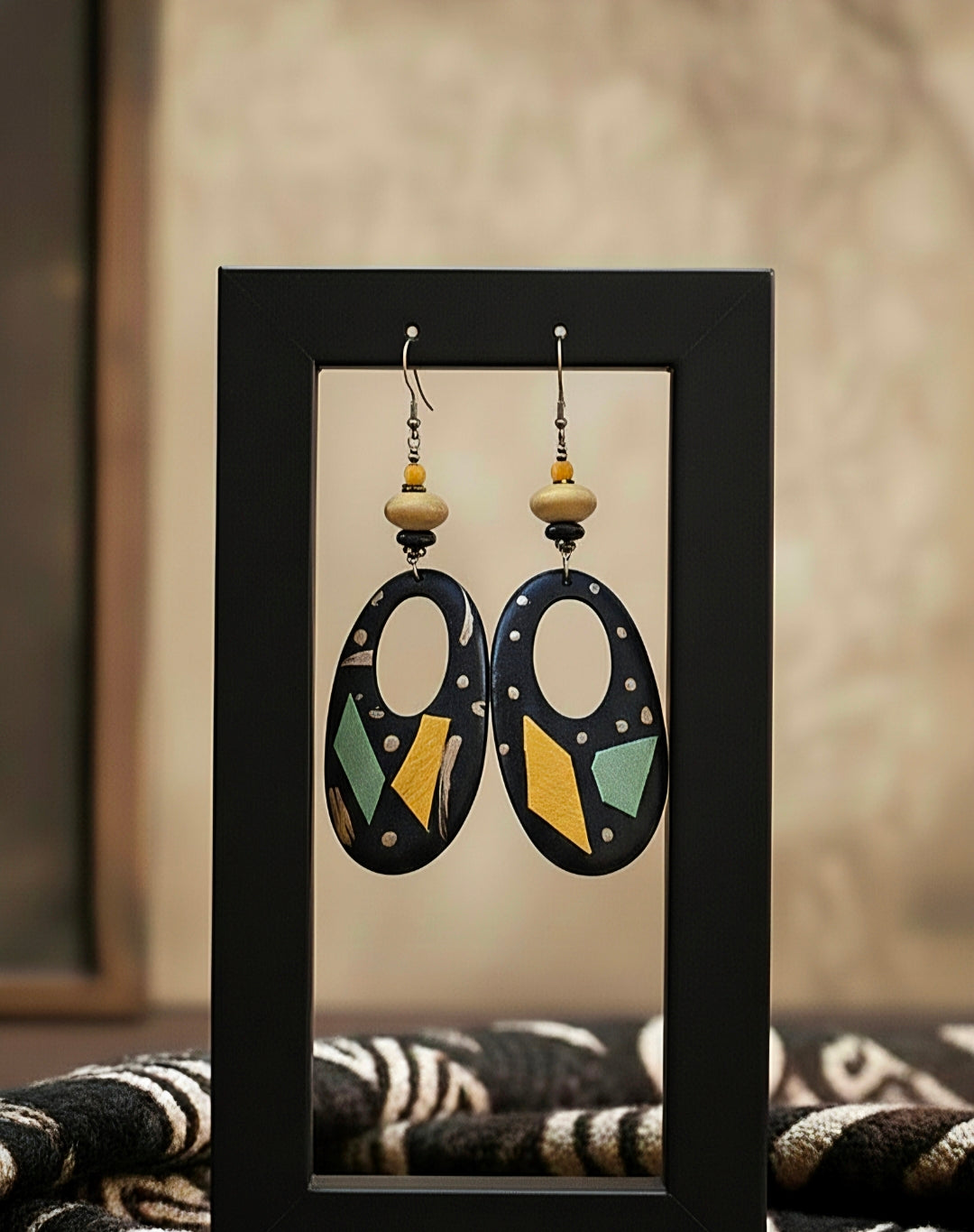 Pair of earrings displayed in a black frame against a neutral background