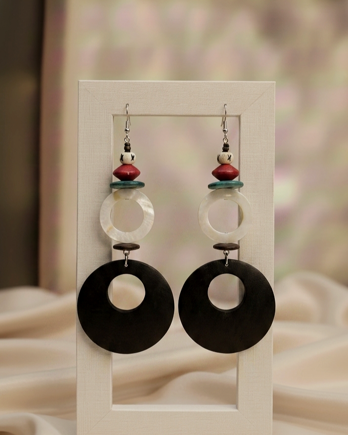 Pair of earrings with black and white circular designs on a display card.