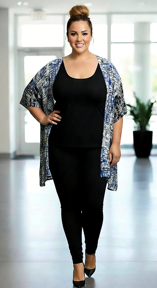 Woman wearing a black outfit with a patterned cardigan in a bright room.