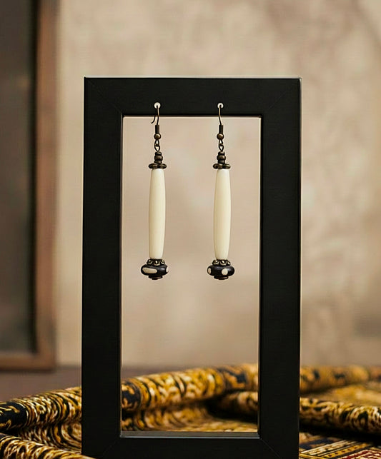 Pair of earrings displayed in a black frame against a neutral background