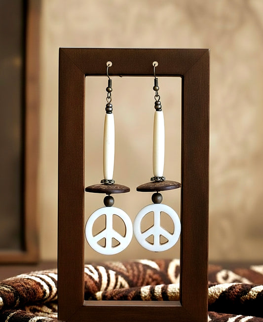 Peace sign earrings displayed in a wooden frame with a neutral background
