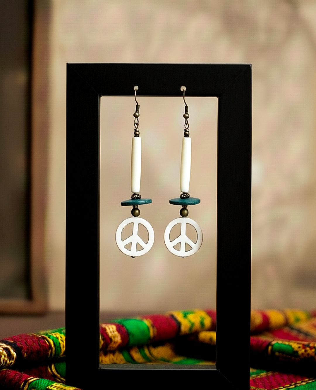 Peace symbol earrings  on a stand against a colorful fabric background