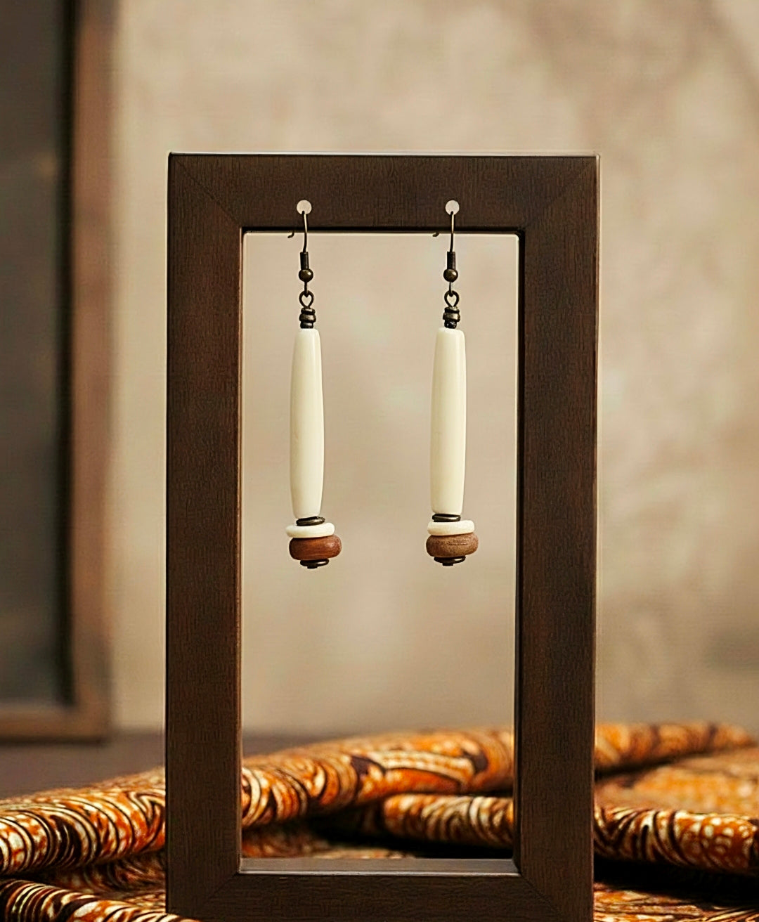 Pair of earrings displayed in a wooden frame with a neutral background