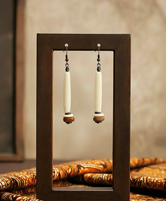 Pair of earrings displayed in a wooden frame with a neutral background