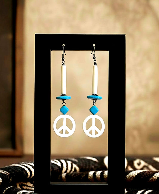 Peace sign earrings with blue accents on a black stand against a neutral background