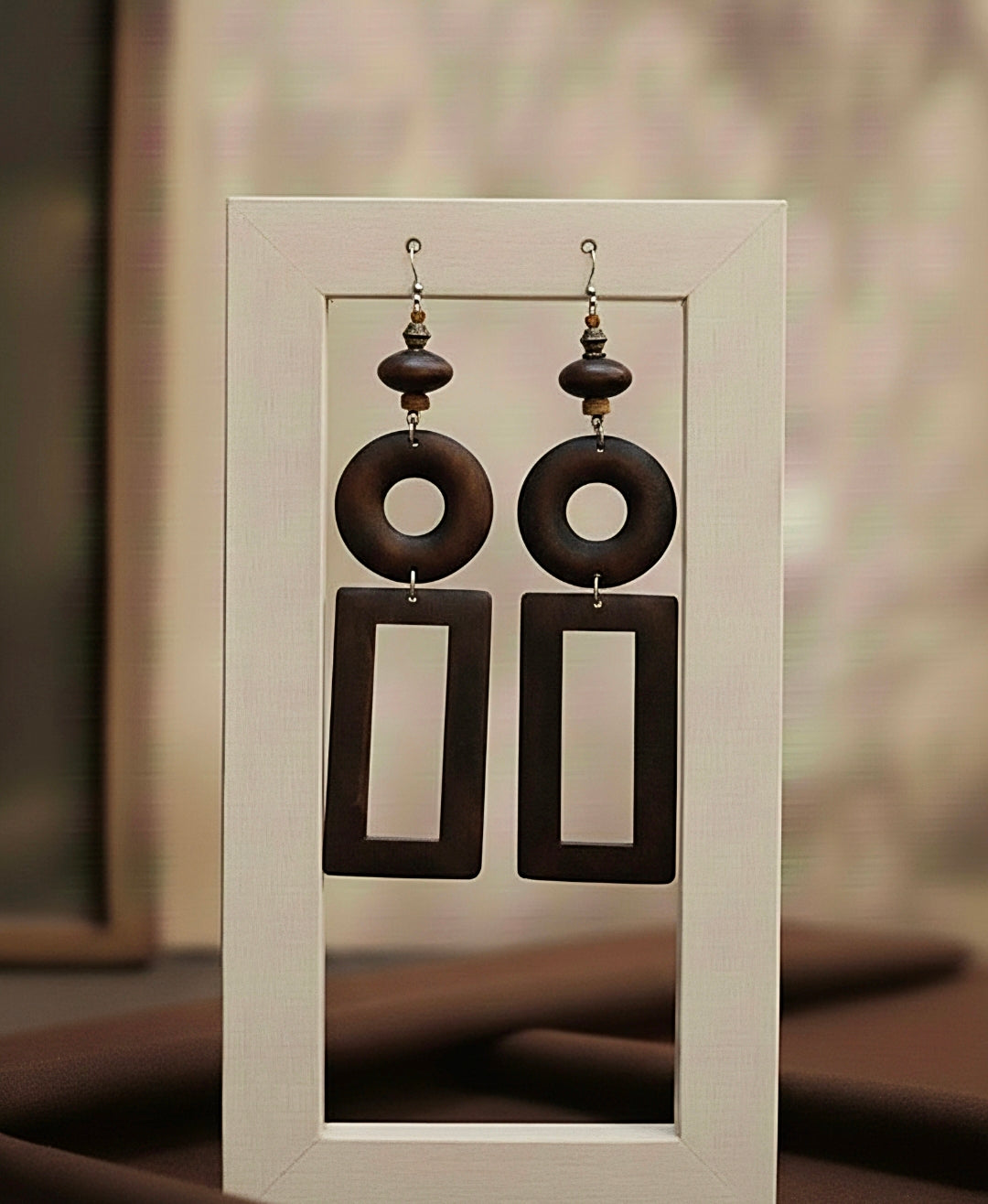Pair of brown wood earrings on a white card with a blurred background