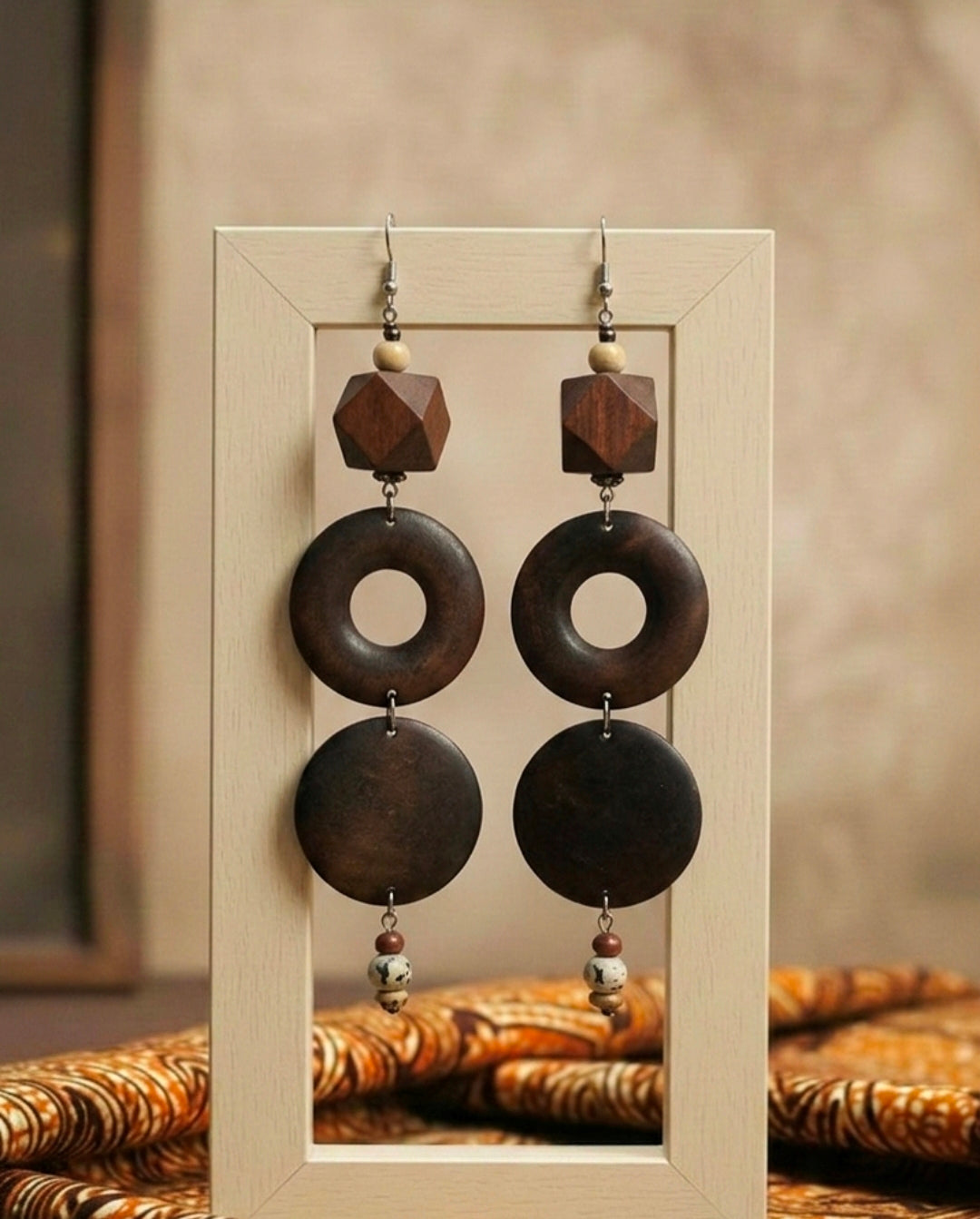 Wooden earrings with circular designs hanging on a wooden stand.
