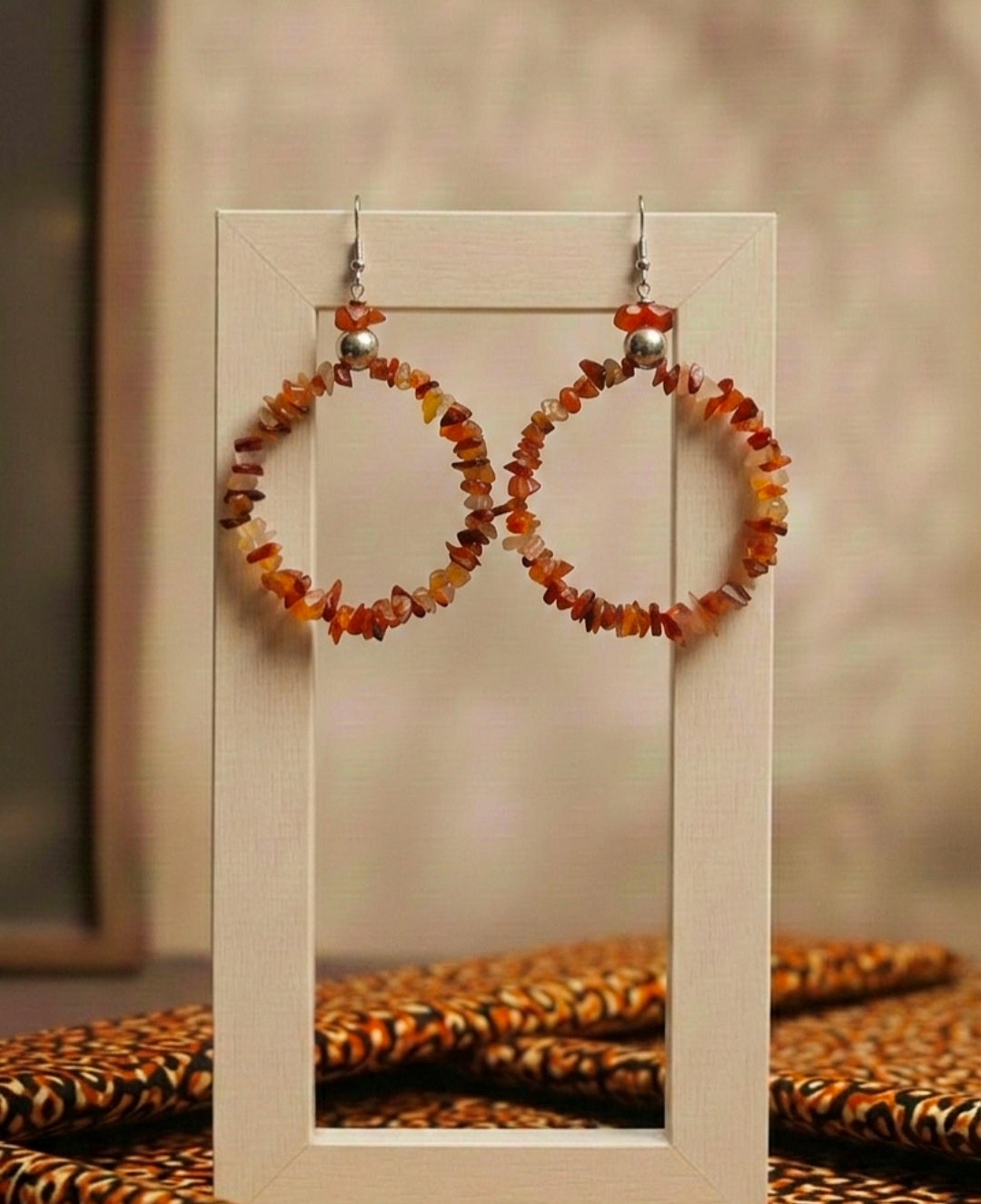 Pair of hoop earrings with amber-colored beads on a display stand.