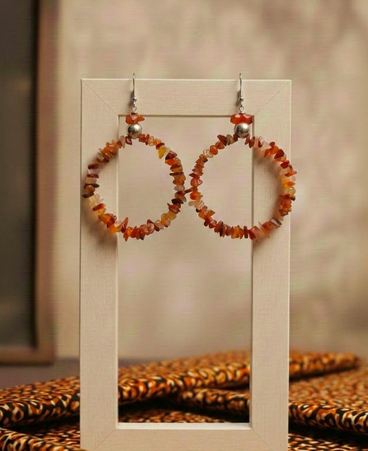 Pair of hoop earrings with amber-colored beads on a display stand.