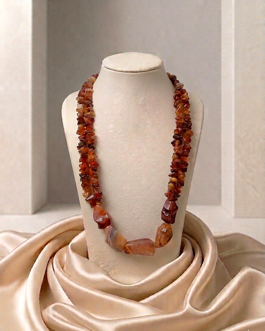 Necklace with amber-colored beads on a mannequin bust against a neutral background