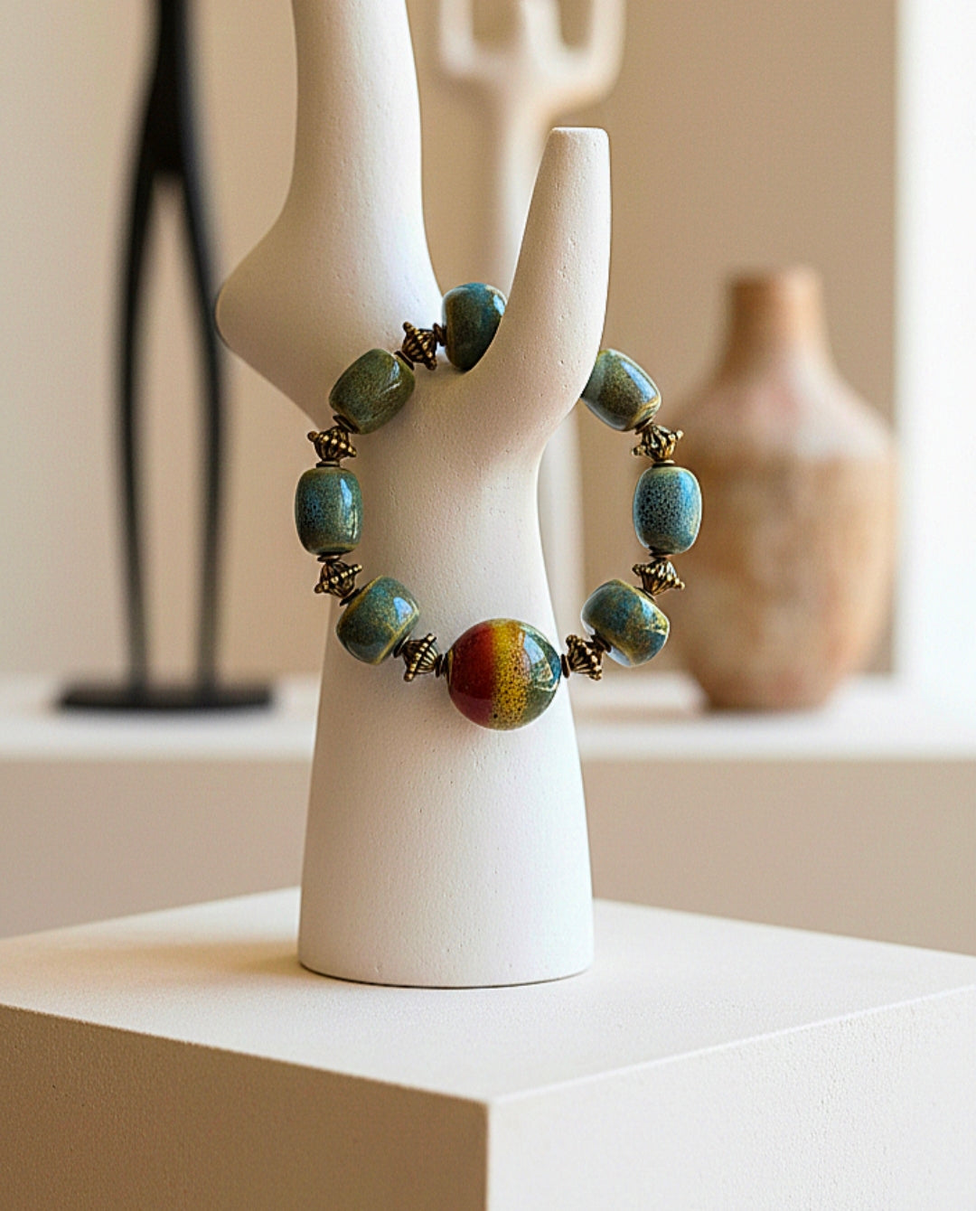 Bracelet with green and brown beads on a white ceramic stand against a neutral background