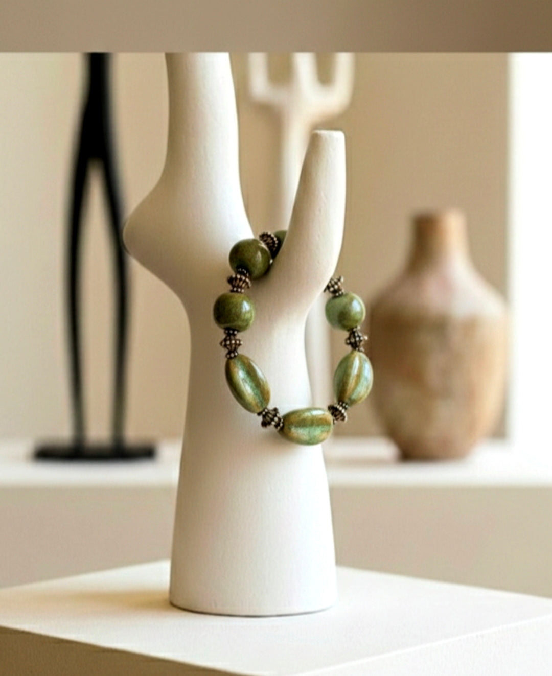 Green beaded necklace on a white mannequin bust with a blurred background