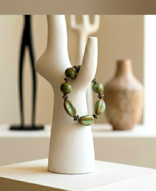 Green beaded necklace on a white mannequin bust with a blurred background