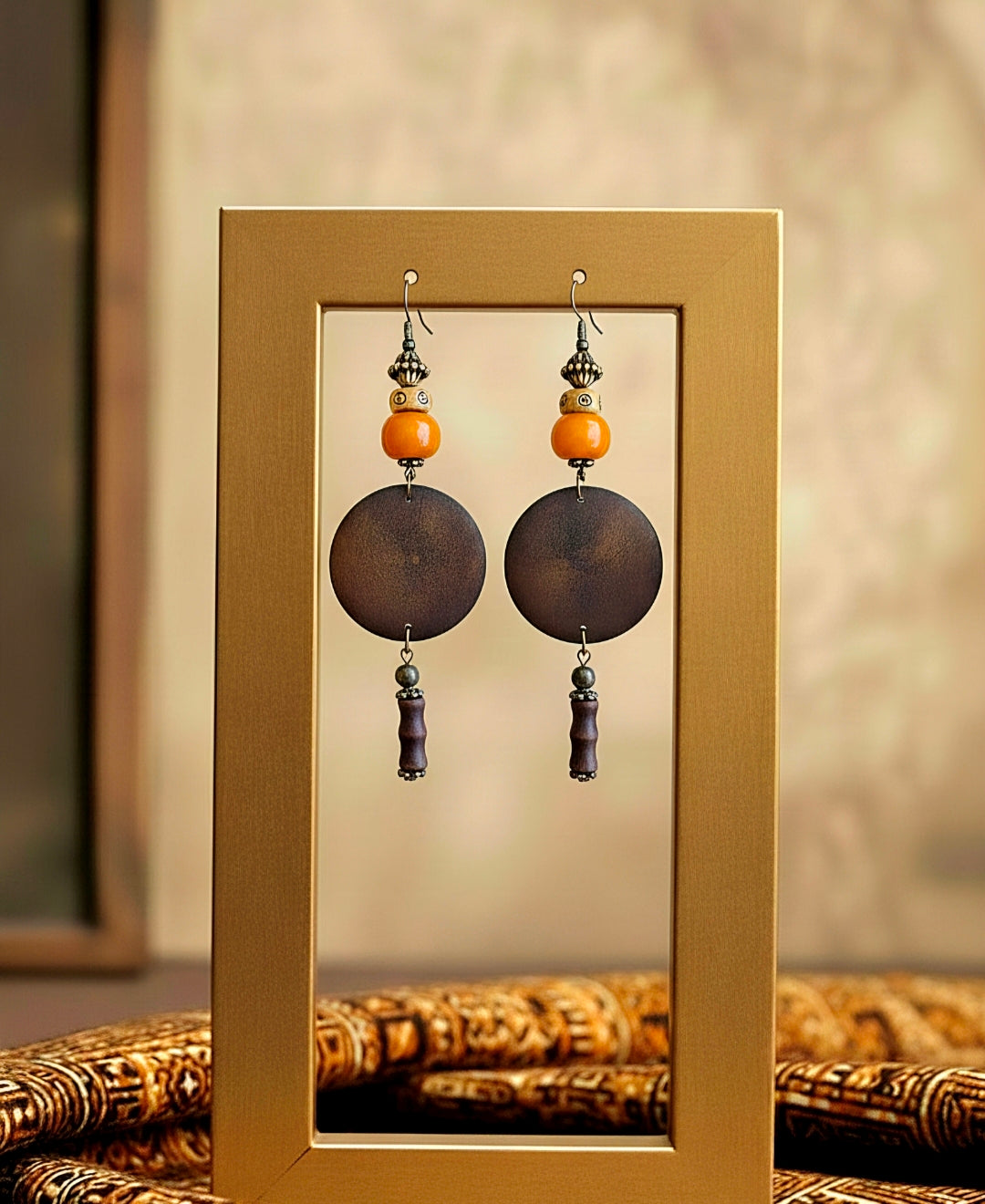 Pair of  brown wood earrings with orange and  beads in a gold frame.