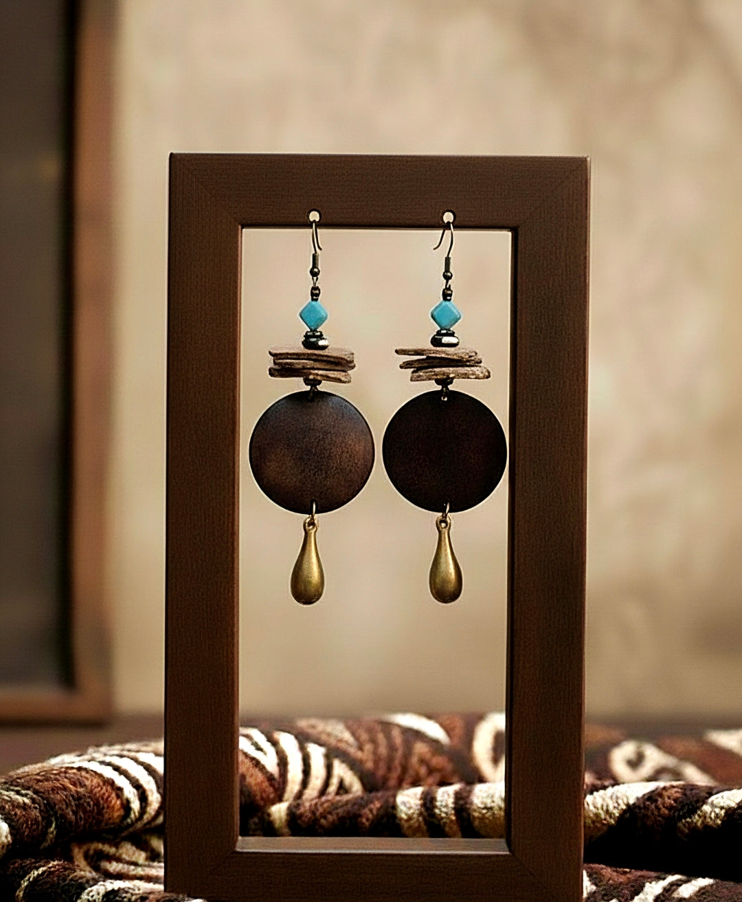 Pair of earrings with wooden and other elements displayed in a wooden frame.