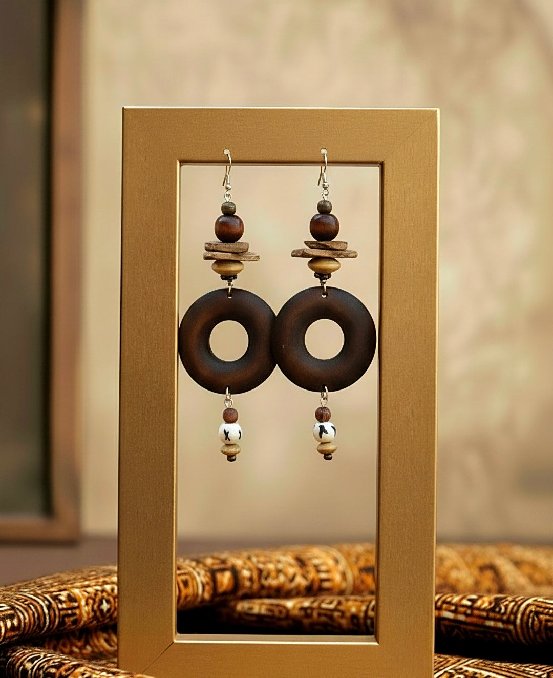Pair of earrings with wooden and metallic elements on a gold stand.