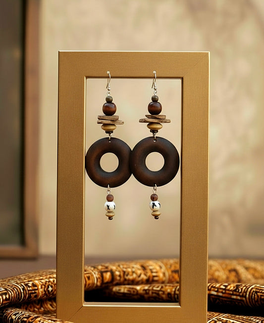 Pair of earrings with wooden and metallic elements on a gold stand.