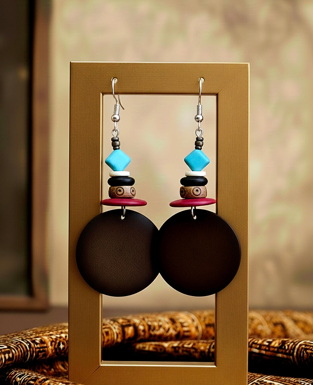 Pair of wood earrings with colorful beads displayed on a mirror