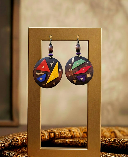 Colorful earrings displayed in front of a mirror on a textured surface.