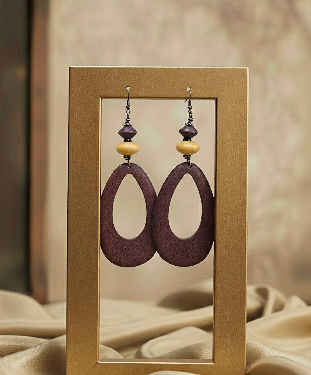 Pair of wood earrings with purple and beige beads in a gold frame.