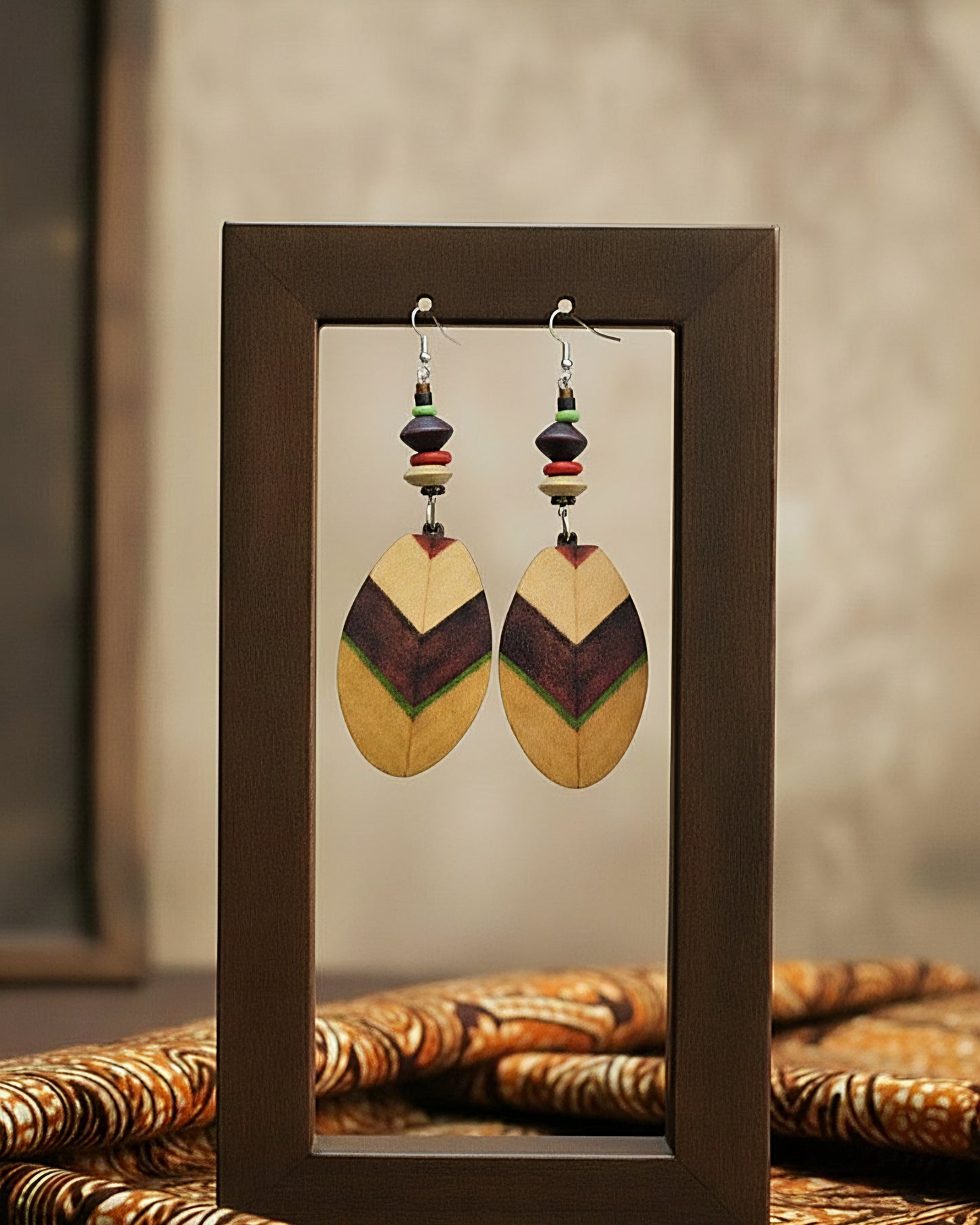 Pair of wooden earrings with colorful beads displayed in a brown frame.