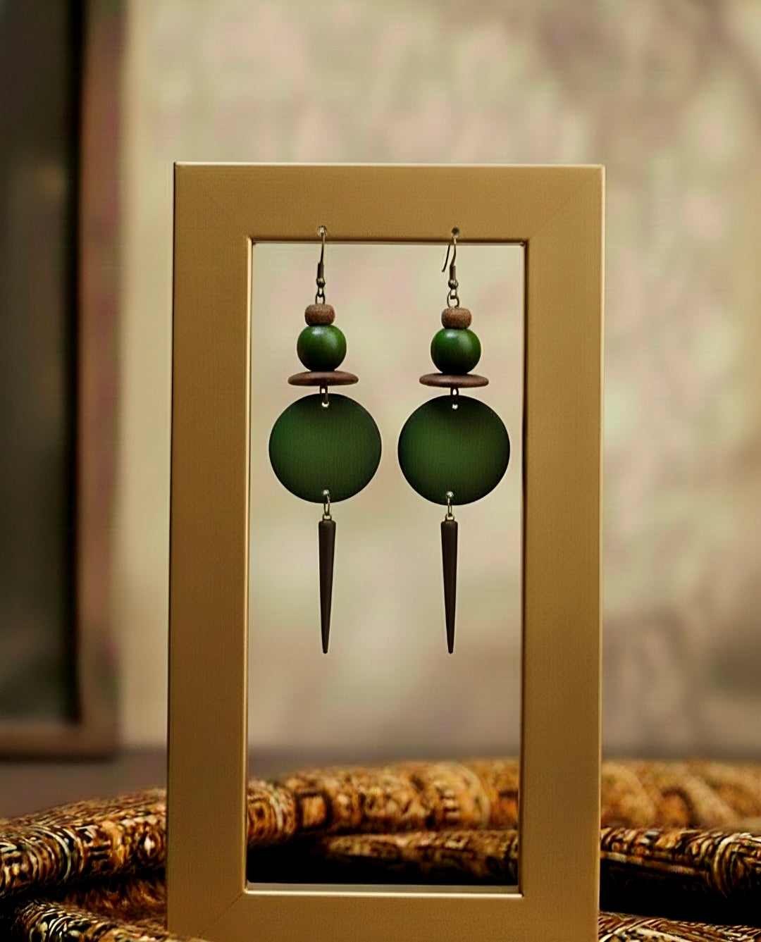 Green beaded earrings with a gold frame on a textured surface