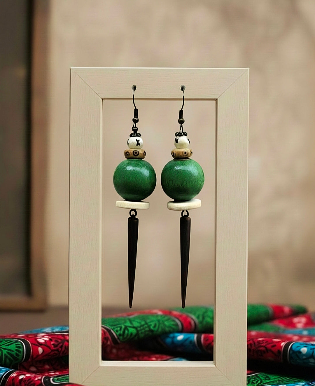 Pair of green earrings with spike accents displayed in a white frame.