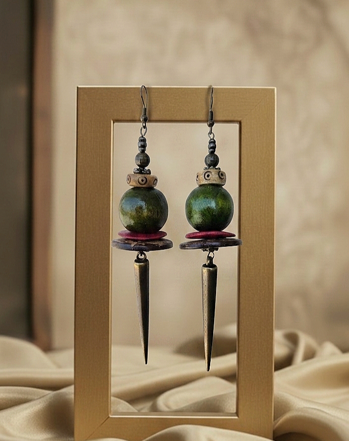 Pair of green spherical earrings with spike-like extensions in a wooden frame.