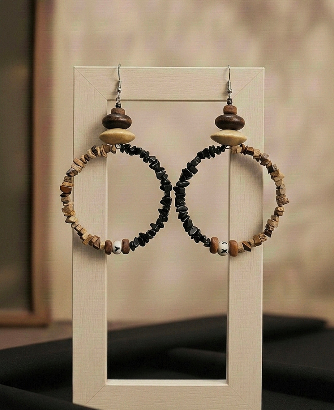 Pair of hoop earrings with wooden and stone beads on a display stand.