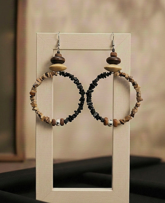 Pair of hoop earrings with wooden and stone beads on a display stand.