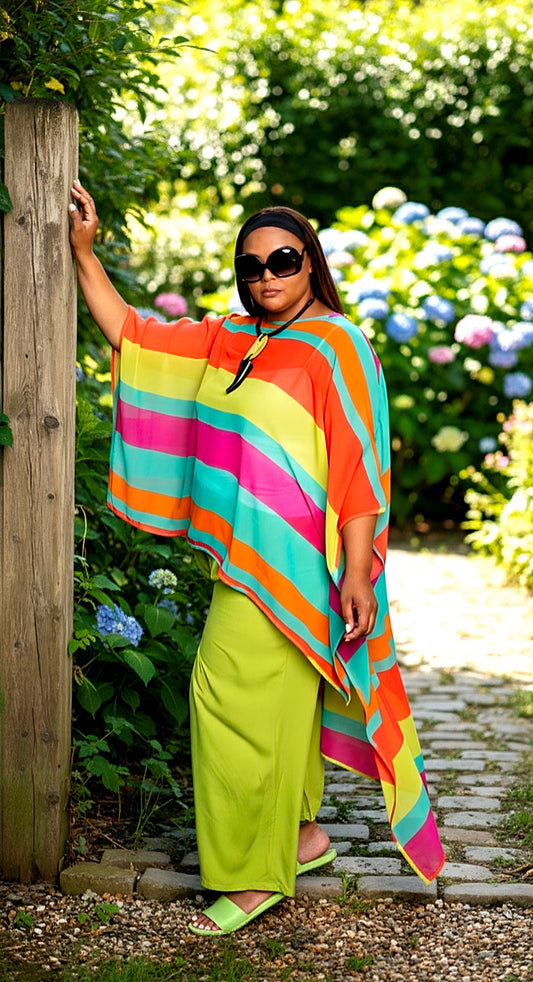Woman wearing a colorful striped poncho and green pants in a garden setting