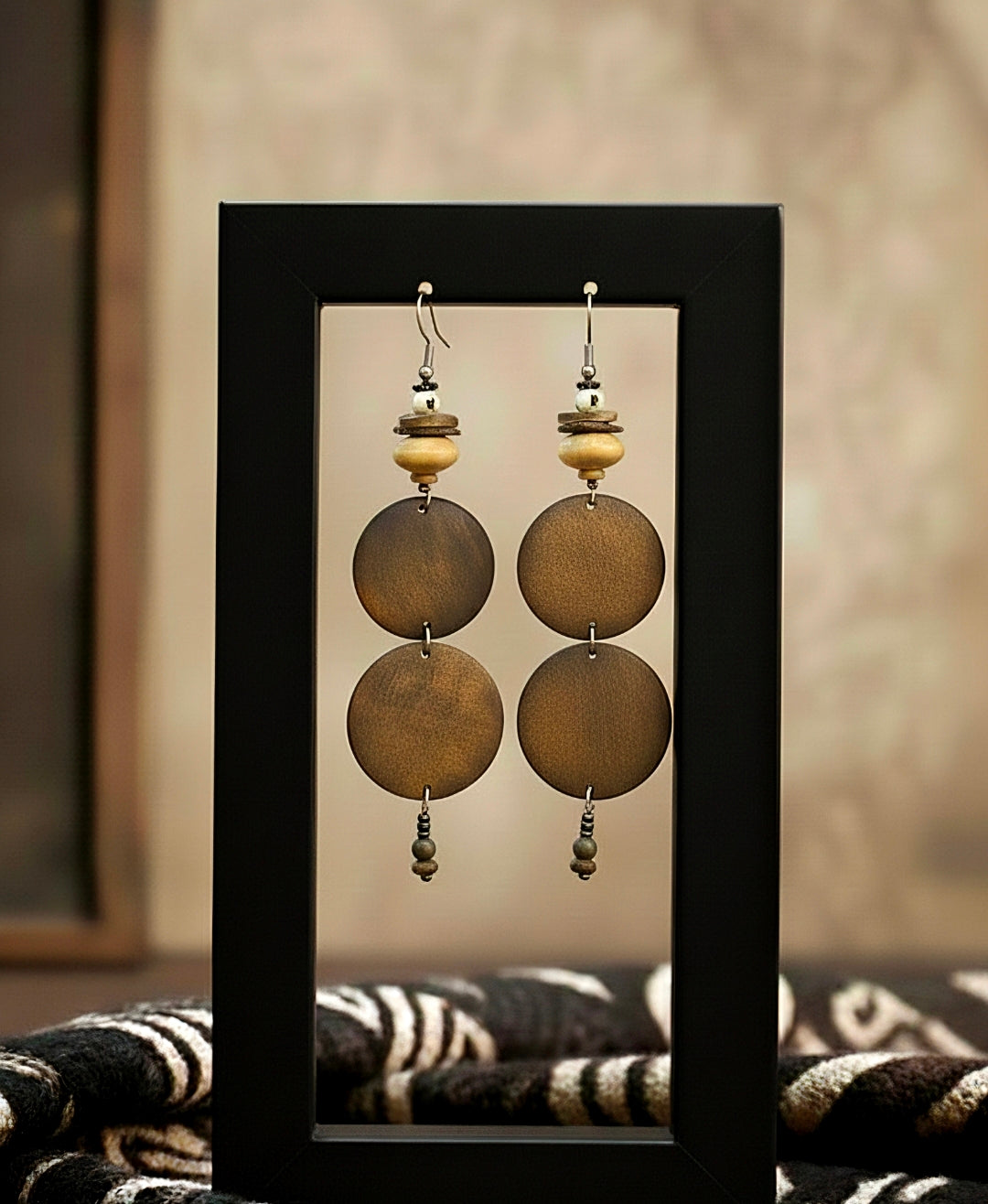 Pair of earrings with round beads in a black frame against a neutral background