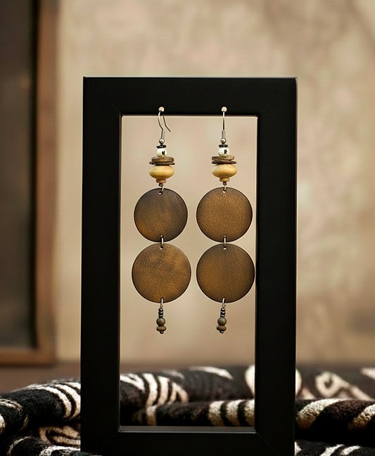Pair of earrings with round beads in a black frame against a neutral background