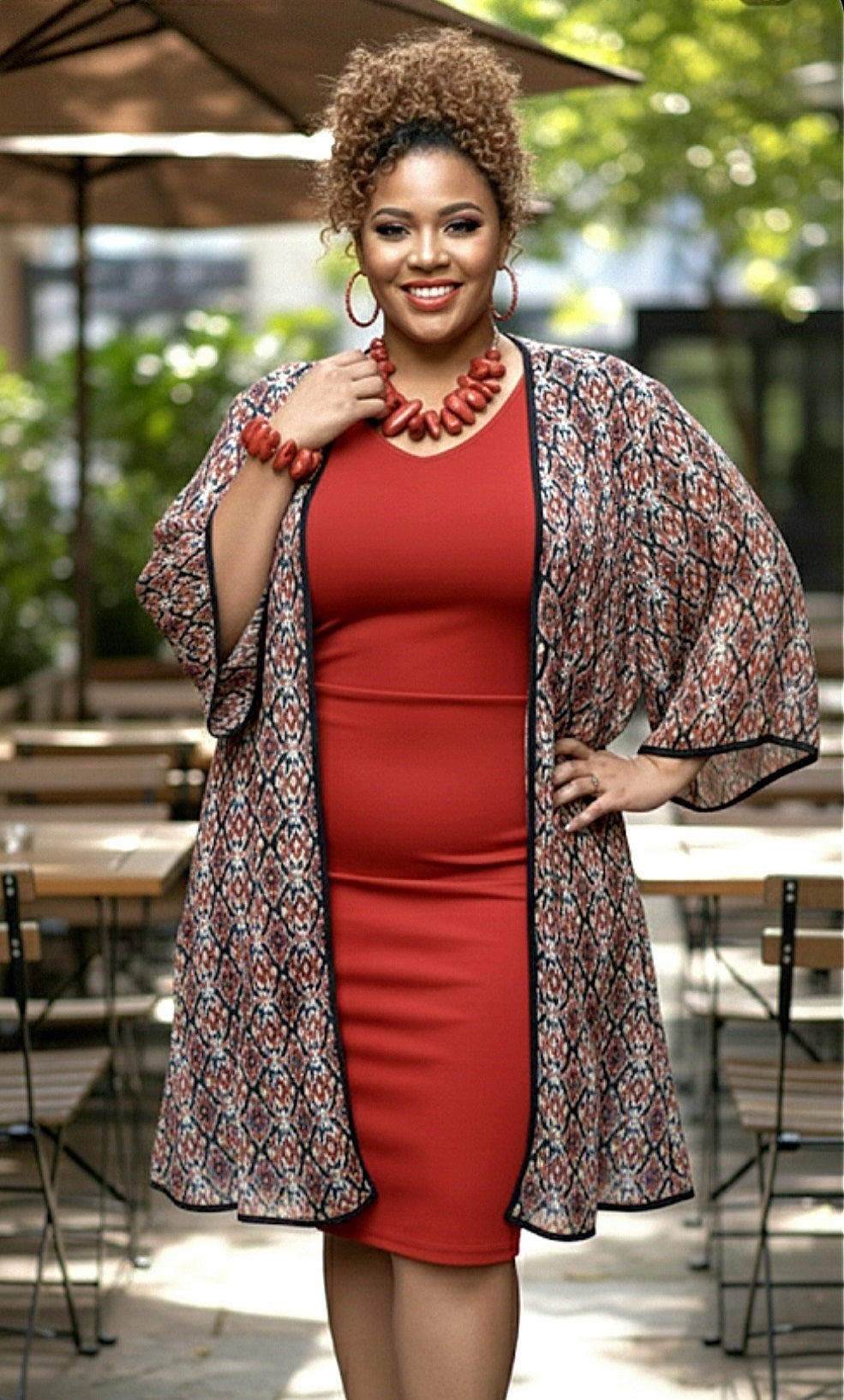 Woman wearing a red dress and patterned cardigan outdoors