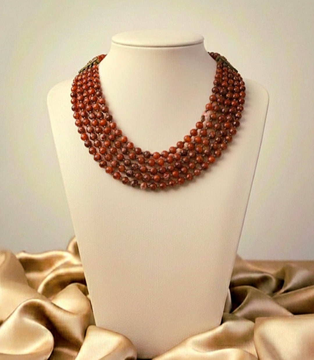 Brown beaded necklace on a mannequin bust with beige fabric background