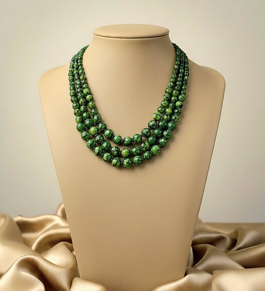 Green beaded necklace on a mannequin bust with beige fabric background