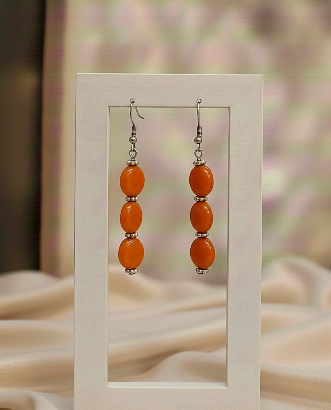 Pair of orange bead earrings on a white background