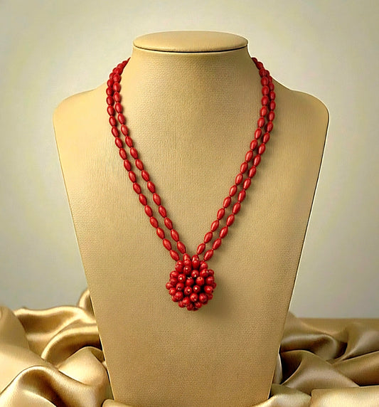 Red beaded necklace on a mannequin bust with a beige background