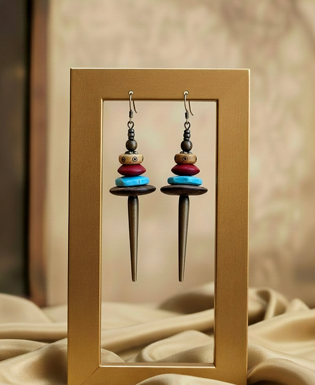 Pair of colorful earrings with a wooden frame on a beige fabric background