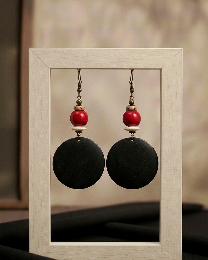 Pair of earrings with black and red beads in a display case.