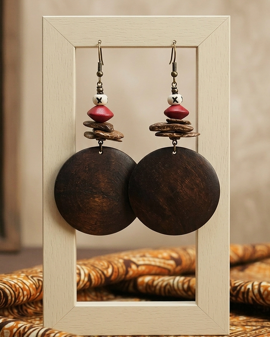 Pair of wooden earrings with red and gold accents in a light wooden frame.