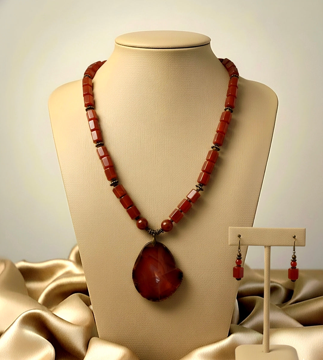 Necklace with large pendant and matching earrings on a mannequin bust.