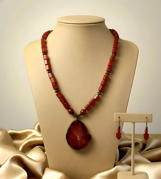 Necklace with large pendant and matching earrings on a mannequin bust.