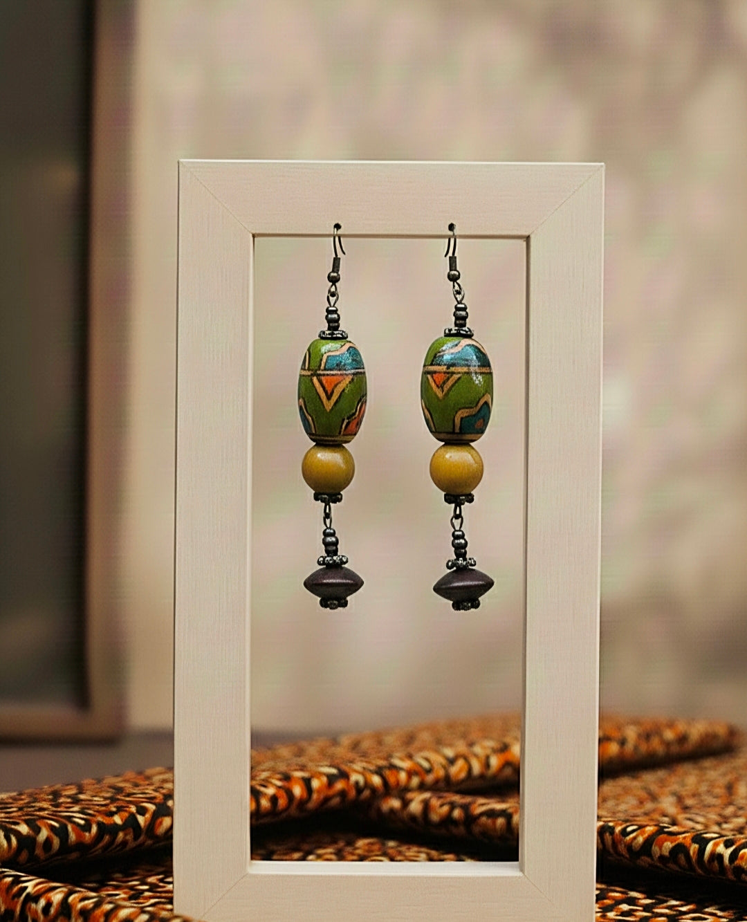 Pair of colorful green beaded earrings displayed in a white frame.